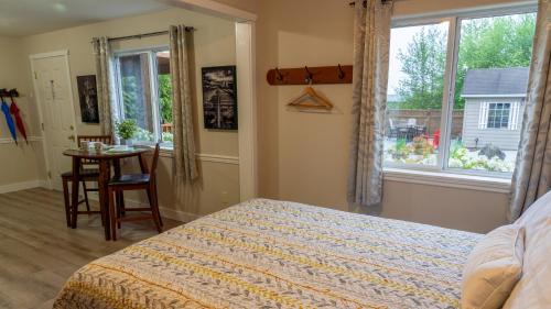 尤克卢利特Wild Pacific Guest Suites的一间卧室配有一张床、一张桌子和一个窗户。