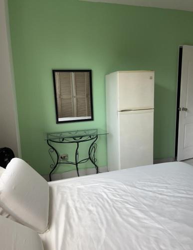 巴拿马城Habitación amplia con baño privado en Apartamento familiar的卧室配有白色的床和冰箱。