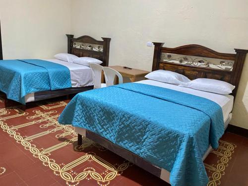 危地马拉Hotel Malybu的配有蓝色棉被的客房内的两张床