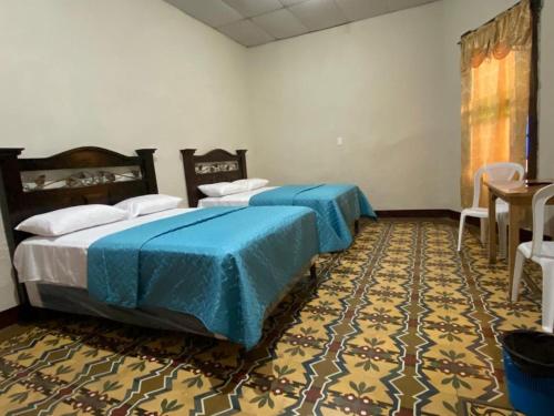 危地马拉Hotel Malybu的一间卧室配有两张带蓝色床单的床,铺有地毯