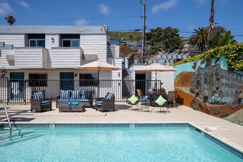 拉古纳海滩Art Hotel Laguna Beach的房屋旁的游泳池配有椅子和遮阳伞