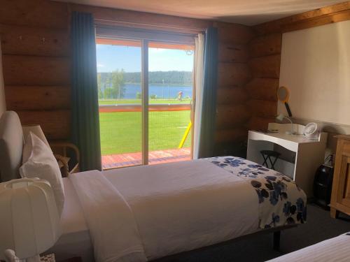 Lac La HacheCariboo Log Guest House的一间卧室设有一张床和一个美景窗户。