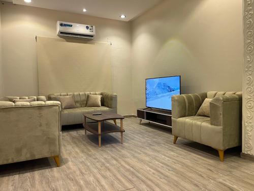 利雅德Hakimdom Hostel的客厅配有2张沙发和1台平面电视