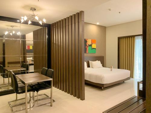 玛琅Savana Hotel & Convention Malang的一间卧室配有一张床铺和一张桌子,还有一间用餐室