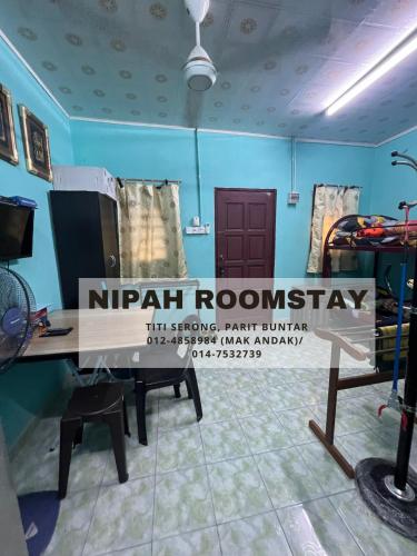 巴力文打NIPAH ROOMSTAY PARIT BUNTAR的一间设有木桌的房间,上面有标志