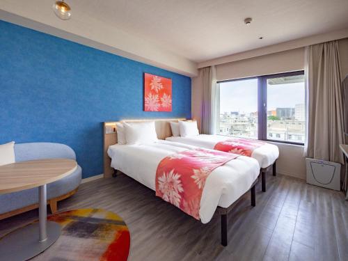 宫古岛Tabino Hotel lit Miyakojima的酒店客房设有两张床和一张桌子。