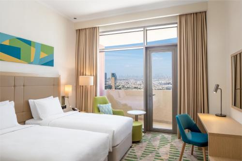 迪拜Holiday Inn & Suites - Dubai Science Park, an IHG Hotel的酒店客房设有两张床和窗户。