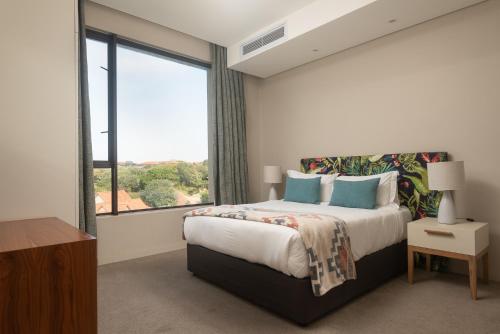 巴利托Indigo 2 Bed Zimbali Suites Sea View的一间卧室设有一张床和一个大窗户