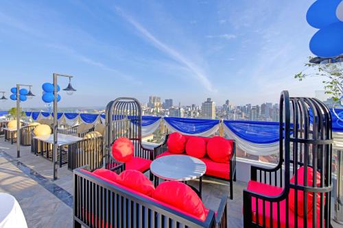 金边Poulo Wai Hotel & Apartment的阳台配有红色的桌椅,享有城市美景。