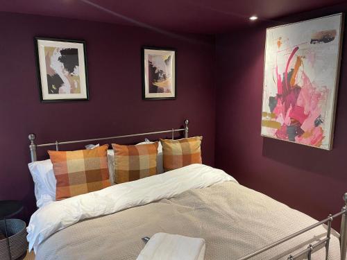 伦敦3BR Apt Near Excel, O2 & City Airport!的一间卧室设有紫色的墙壁和一张带枕头的床