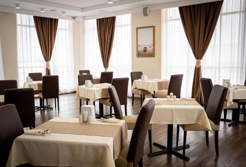 BautinoChagala Bautino Hotel的餐厅设有白色的桌椅和窗户。
