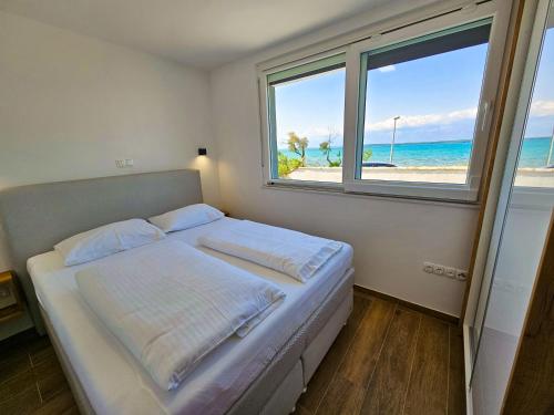 宁Apartmani Adria的一间卧室配有一张床,享有海滩美景
