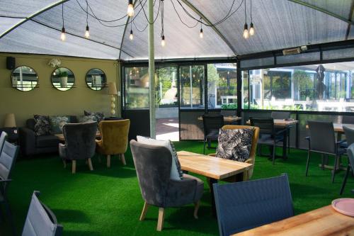 西萨默塞特Silver Forest Boutique Hotel and Spa的餐厅配有桌椅,铺有绿色地毯。