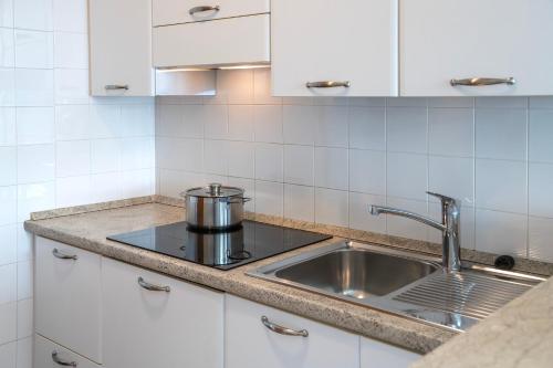 托尔博莱Residence Casa al Sole Apartments的厨房配有不锈钢水槽和白色橱柜