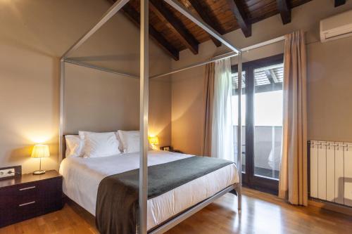 利维亚伯纳特德索酒店的一间卧室设有一张带大窗户的天蓬床