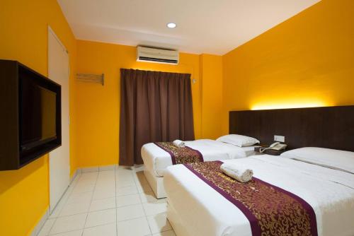 马六甲SC Hotel Melaka的一间酒店客房,设有三张床和一台平面电视