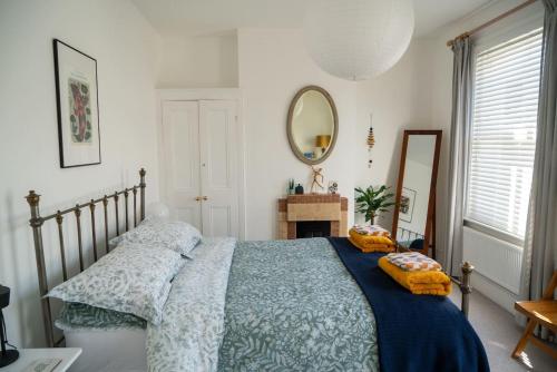 拉姆斯盖特Stylish two bedroom terrace with garden的一间卧室配有一张带蓝色毯子和镜子的床