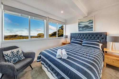 荷斯安山The Penthouse @ Alpine Haven的一间卧室配有一张床、一把椅子和窗户。