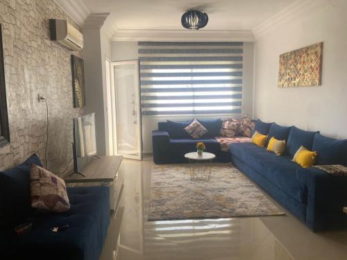 艾西拉lovely and chic Appartment in asilah marina golf的客厅配有蓝色的沙发和桌子