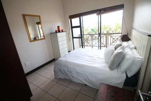 马盖特Topanga 70, Uvongo的一间卧室配有带白色枕头的床和阳台