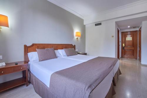 科尔多瓦Crisol Jardines de Córdoba的卧室配有一张白色大床和木制床头板