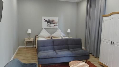 Neu GaarzNeu möbliertes 1 - Zimmerapartment mitten in der Natur的客厅配有蓝色的沙发和床。