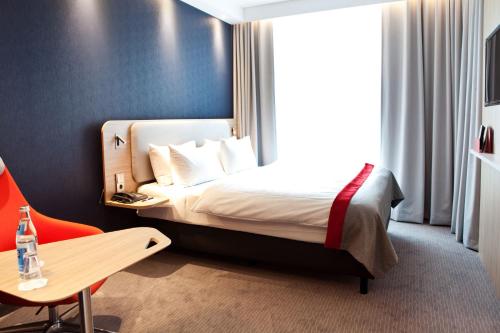 锡根锡根快捷假日酒店的酒店客房,配有床、桌子和椅子