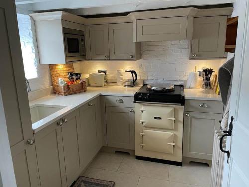 West BrettonWoodpecker Cottage的厨房配有白色橱柜和炉灶烤箱。