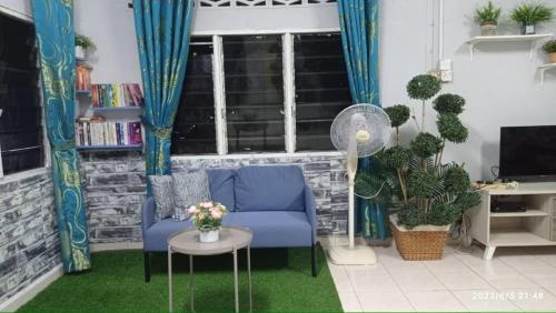 居林Ketupat Palas Homestay的客厅配有蓝色的沙发和桌子