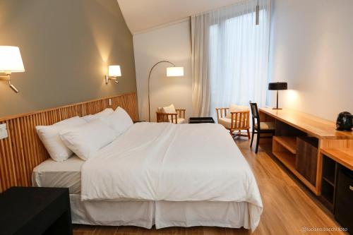 厄尔查尔坦Kaulem Hotel Boutique的一间酒店客房,配有一张白色的床和一张书桌