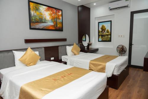 Tuyên QuangAnh Anh Luxury Hotel的酒店客房设有两张床,墙上挂有绘画作品