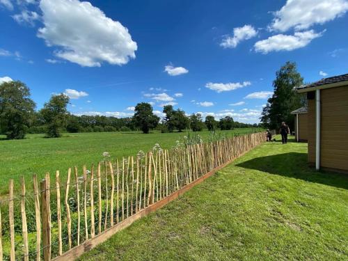 Jubbega-SchuregaPipowagens bij Pannenkoekenrestaurant & Camping De Koppenjan 'Een uniek verblijf met kinderspeelboerderij'的田野上用木杆围栏