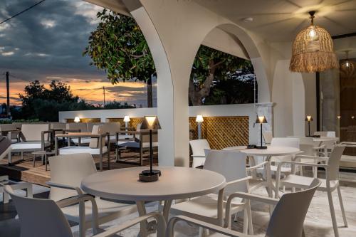 卡拉马孔Nikon Boutique Hotel的一间设有白色桌椅的餐厅,享有日落美景