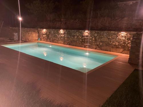 多尔切阿夸Gli Orti dei Doria di dolceacqua的一座带石墙的夜间游泳池