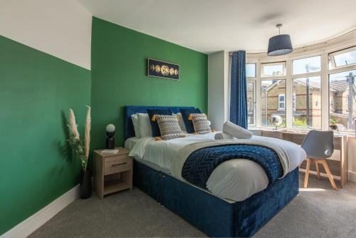 南安普敦Spacious Southampton House Sanctuary in the City的一间卧室设有蓝色的床和绿色的墙壁