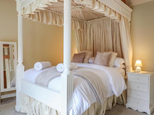 迪斯The Stables at Hall Barn的卧室配有带白色床单和枕头的天蓬床。