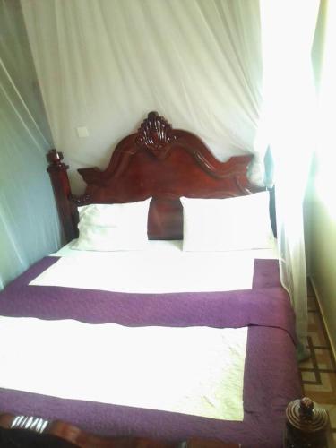 卡巴莱City Max hotel Kabaale的一间卧室配有一张带白色床单的木床