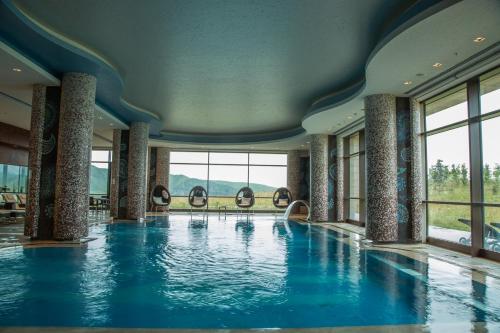 沙达格Shahdag Hotel & Spa的一座带窗户的建筑里,有一个蓝色的游泳池