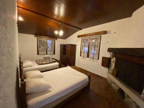 JaujacNOUVEAU Maison de la place的一间卧室设有两张带白色床单和木制天花板的床。