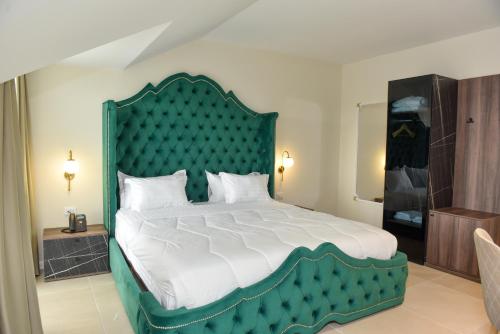 斯库台Hotel Royal的一间卧室配有一张大床和绿色床头板