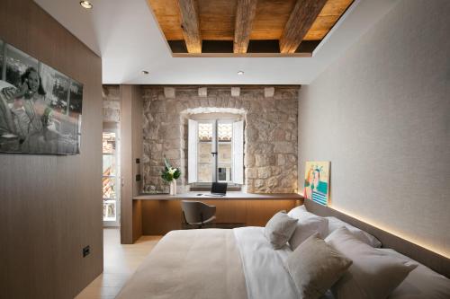 杜布罗夫尼克Villa Lapisa的一间卧室设有一张大床和石墙