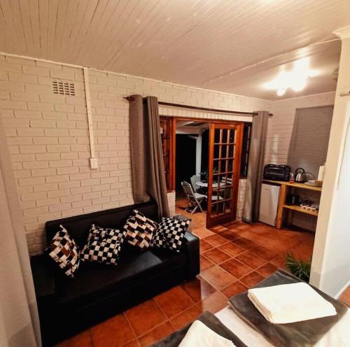 霍维克Woodgate Cottage的客厅配有带枕头的黑色沙发