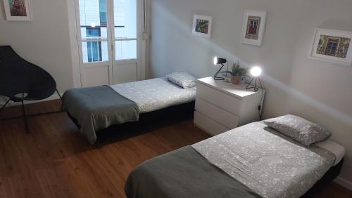 里斯本Memoria 49的一间卧室设有两张床、一个梳妆台和窗户。