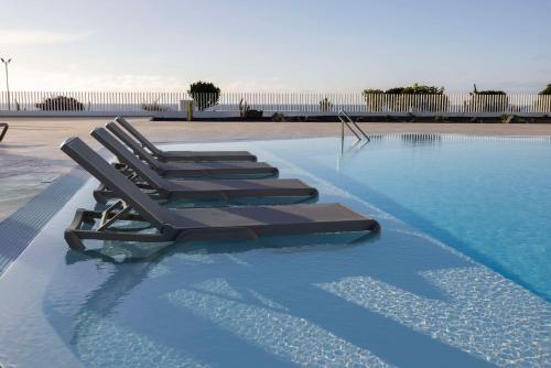 科斯塔特吉塞Radisson Blu Resort, Lanzarote Adults Only的游泳池里一排躺椅