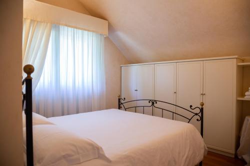 里乔内Villa Rolls - Porzione di Villa con piscina,giardino e parcheggi的卧室配有白色的床和窗户。