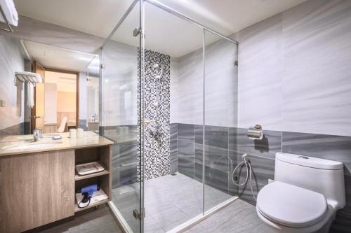 台中市美之旅商务饭店的一间带卫生间和玻璃淋浴间的浴室