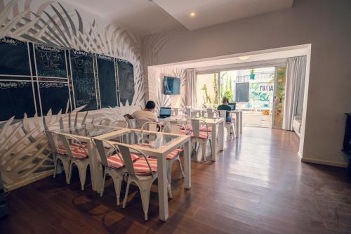 门多萨Fuxia Jungle Hostel的一间设有桌子的用餐室,有人坐在用餐室