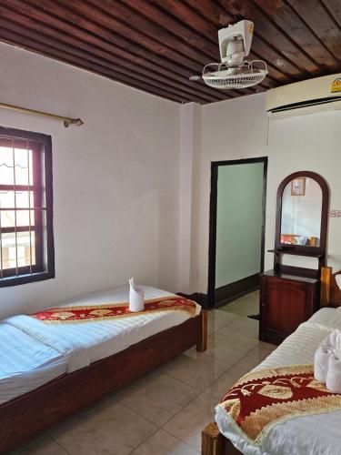 琅勃拉邦Chitlatda Bila House的一间卧室配有两张床和镜子