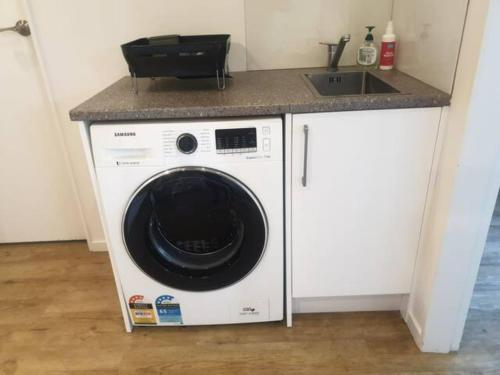 波里鲁阿New, Cosy & Private 1-Bedroom & Living Flat的洗涤槽下的洗衣机