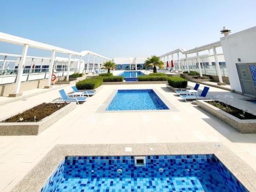 拉斯阿尔卡麦Beach Dream - a luxury 1 bedroom apartment with direct beach access的一座带椅子的游泳池以及一座建筑